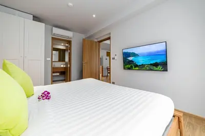 a bedroom with a white bed with a tv on the wall at Beachside 2 bedrooms apartment 200 meters to Bang Tao Beach Manage by OCEAN HUB in Bang Tao Beach