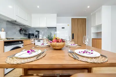 a kitchen with a wooden table with plates and wine glasses at Beachside 2 bedrooms apartment 200 meters to Bang Tao Beach Manage by OCEAN HUB in Bang Tao Beach