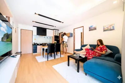 a woman sitting on a couch in a living room at Hillside 2BR Apartment with Pool & Gym 5 Min to Kamala Beach 48RK in Kamala Beach