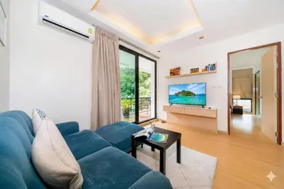 a living room with a blue couch and a large window at Hillside 2BR Apartment with Pool & Gym 5 Min to Kamala Beach 48RK in Kamala Beach