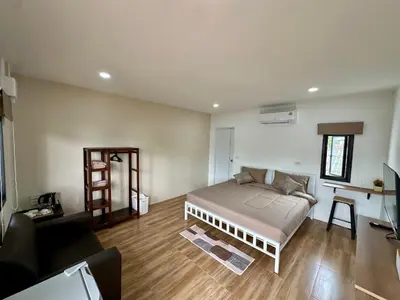 a bedroom with a bed and a living room at Bike Works Inn Bang Tao in Ban Thalat Choeng Thale