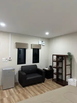a living room with a black couch and a shelf at Bike Works Inn Bang Tao in Ban Thalat Choeng Thale