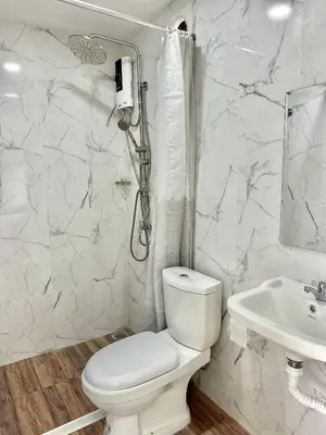 a white bathroom with a toilet and a sink at Bike Works Inn Bang Tao in Ban Thalat Choeng Thale