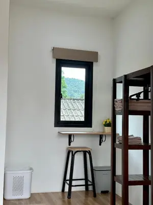 a room with a window and a stool at Bike Works Inn Bang Tao in Ban Thalat Choeng Thale