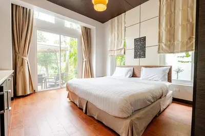 a bedroom with a large bed and a large window at Tree Resort Palai v2 in Chalong