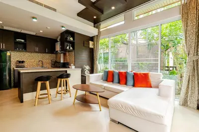a living room with a white couch and a kitchen at Tree Resort Palai v2 in Chalong