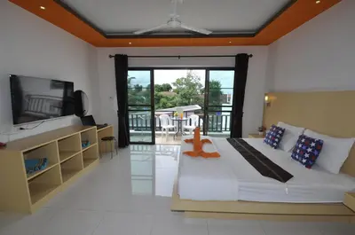 a bedroom with a bed and a tv and a balcony at Duangjai Residence, Rooms & Apartments in Rawai Beach