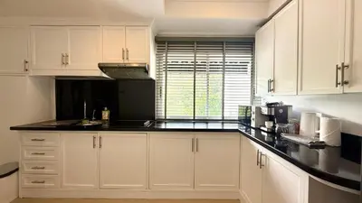 a kitchen with white cabinets and a black counter top at Palace - Spacious 1 bedroom Condo with shared Pool in Patong Beach