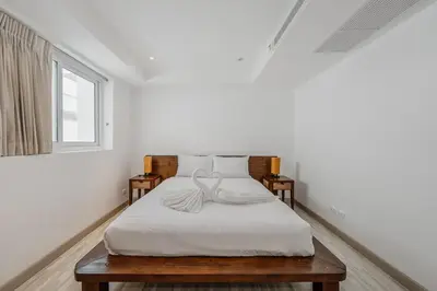 a white bedroom with a bed with white sheets and a window at C236 Best Pool &Sea View 2BR Condo Prime Location in Karon Beach