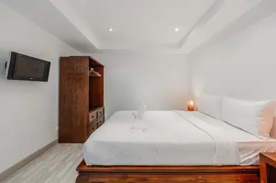 a bedroom with a white bed and a tv at C236 Best Pool &Sea View 2BR Condo Prime Location in Karon Beach