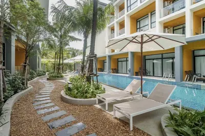 a resort pool with two lounge chairs and an umbrella at Pool View Condo 2204 Wyndham Garden Resort in Phuket Town