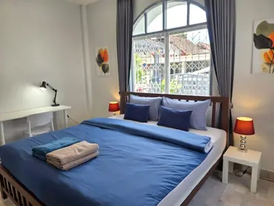 a bedroom with a large bed with blue sheets and a window at Moonlight Naka in Ban Rangeng