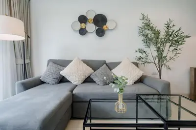 a living room with a blue couch and a glass table at Cassia Exclusive Lake View Condo Bang Tao Beach in Phuket Town