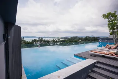 a swimming pool with people laying on the deck at Apartment Seaview Rooftop Pool Surin beach 650m in Surin Beach