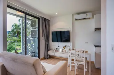 a living room with a couch and a flat screen tv at Apartment Seaview Rooftop Pool Surin beach 650m in Surin Beach