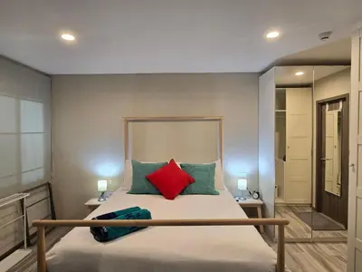 a bedroom with a bed with red and green pillows at Pool Side Retreat 1 BED - TC-B105 in Phuket Town