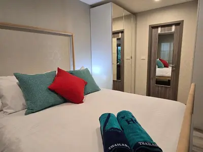 a bedroom with a white bed with red and green pillows at Pool Side Retreat 1 BED - TC-B105 in Phuket Town