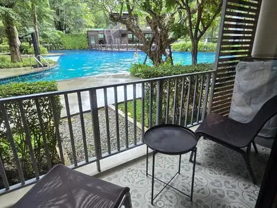 a balcony with two chairs and a swimming pool at Pool Side Retreat 1 BED - TC-B105 in Phuket Town