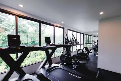 a gym with treadmills and ellipticals in a room with windows at FantaSea condo Kamala 205 in Kamala Beach
