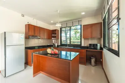 a kitchen with wooden cabinets and a white refrigerator at 3 Bedrooms villa walking distance to Rawai beach in Rawai Beach
