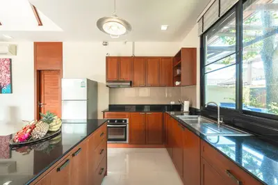 a kitchen with wooden cabinets and a large window at 3 Bedrooms villa walking distance to Rawai beach in Rawai Beach