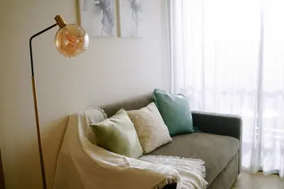 a living room with a couch with pillows and a lamp at Ozone Sky View Residence in Laguna Phuket