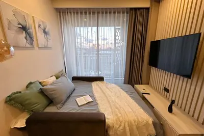 a bedroom with a bed with a television on a wall at Ozone Sky View Residence in Laguna Phuket
