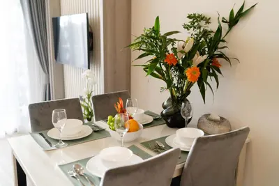 a dining room table with a vase of flowers at Ozone Sky View Residence in Laguna Phuket