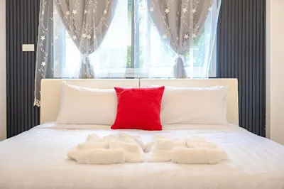a bed with two white pillows and a red pillow at Platinum Villa Rawai in Rawai Beach