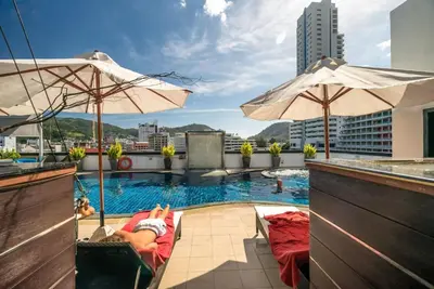 a person laying on a chair next to a swimming pool at L02 Bangla Suites Modern Studio On Bangla Road in Patong Beach