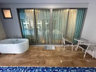 a bathroom with a tub and a table and chairs at The Regent Bang Tao Beach in Phuket