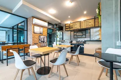 a restaurant with tables and chairs and a kitchen at Phuket Five Fortune Holiday Hotel in Rawai Beach