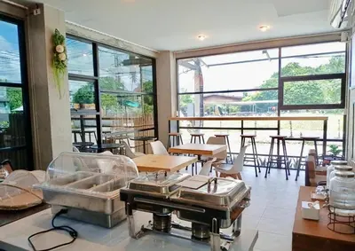 a restaurant with tables and chairs and large windows at Phuket Five Fortune Holiday Hotel in Rawai Beach
