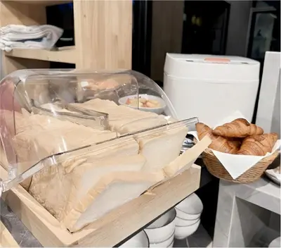 a plastic container filled with bread and pastries on a counter at Phuket Five Fortune Holiday Hotel in Rawai Beach
