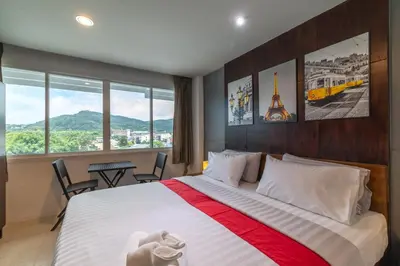 a bedroom with a large bed with a view at Phuket Five Fortune Holiday Hotel in Rawai Beach