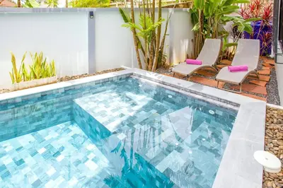 a swimming pool with two chairs and a swimming pool at 150 m from a paradise beach 3 bedrooms pool in Klong Muang Beach