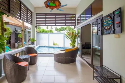a living room with a pool and some chairs and a table at 150 m from a paradise beach 3 bedrooms pool in Klong Muang Beach