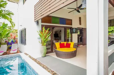 a patio with a yellow and red chair next to a pool at 150 m from a paradise beach 3 bedrooms pool in Klong Muang Beach