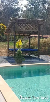 a picnic table with an umbrella next to a pool at Baan ton mai 2 bedrooms 400 m from the beach in Klong Muang Beach