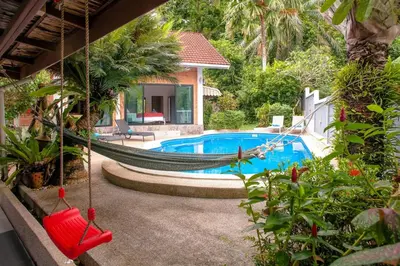 a hammock in front of a house with a pool at Villa with private pool and mountain views in Ban Khlong Son