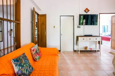 a living room with an orange couch and a tv at Villa with private pool and mountain views in Ban Khlong Son