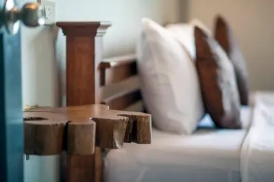 a close up of a bed with pillows and a wooden stool at Jaccuzi House 5 pl 200 m from a beautiful beach in Klong Muang Beach