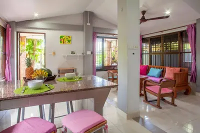 a kitchen and living room with pink chairs and a table at House 4 people sea view 100 m from the beach in Klong Muang Beach