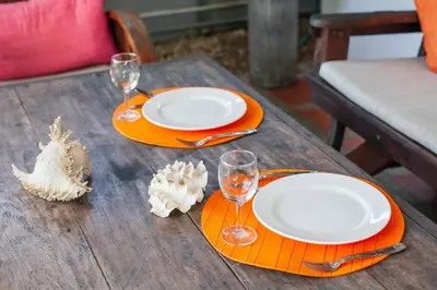 a wooden table with two plates and glasses on it at House 4 people sea view 100 m from the beach in Klong Muang Beach