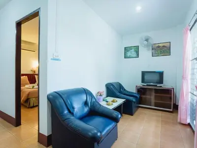 a living room with two chairs and a television at Rabbit Mansion Patong Hotel in Patong Beach