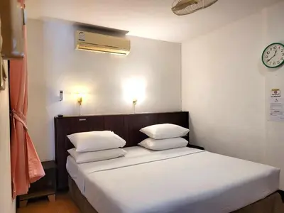a bedroom with a bed with white sheets and pillows at Rabbit Mansion Patong Hotel in Patong Beach