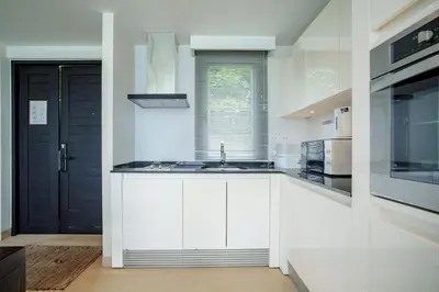 a kitchen with white cabinets and a black door at Raya Villa 2 Bed Beachfront Villa Private Pool in Rawai Beach