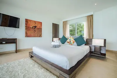 a bedroom with a large white bed and a television at Raya Villa 2 Bed Beachfront Villa Private Pool in Rawai Beach