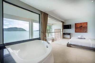 a bathroom with a tub and a bed and a large window at Raya Villa 2 Bed Beachfront Villa Private Pool in Rawai Beach