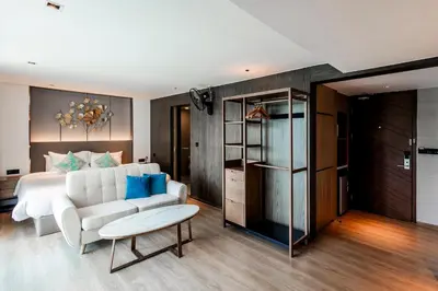 a bedroom with a bed and a couch and a table at La Vita Phuket by Beringela in Rawai Beach